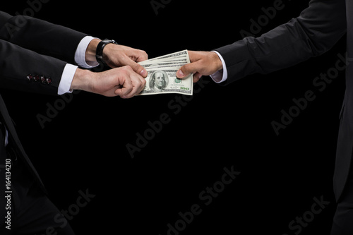 cropped view of businessman giving money and bribing business partner, isolated on black