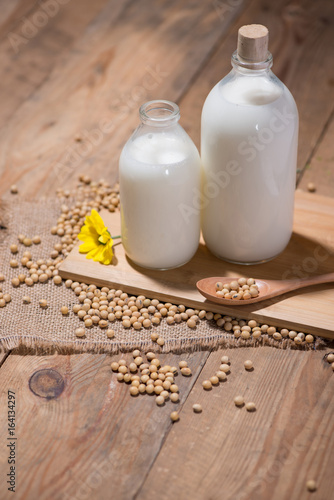 Soy milk or soya milk and soy beans in spoon on wooden table.