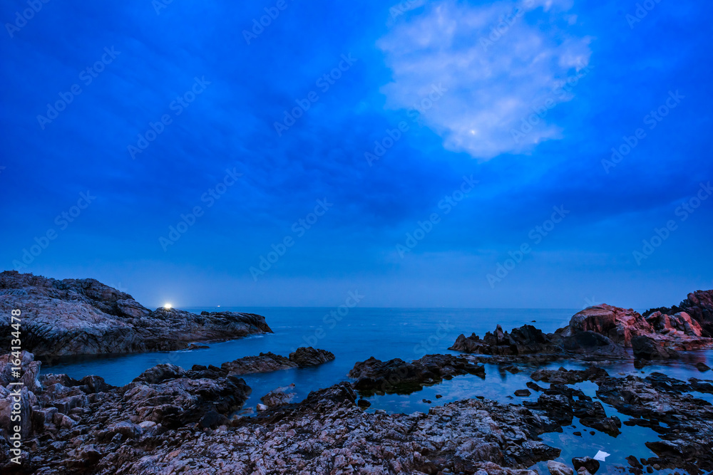 A landscape of the beach at dawn full of rocks.
