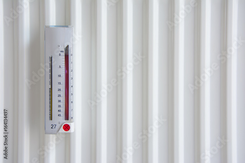 Measuring heating instrument with yellow and red columns on white radiator