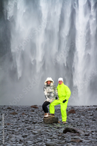 Two beautiful tourists in front of the mighty Skogafoss waterfall in Iceland