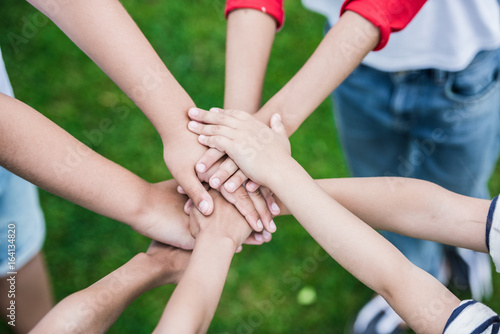 Cropped shot of children stacking hands while standing on green grass © LIGHTFIELD STUDIOS