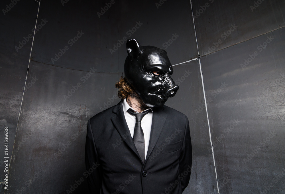 A corporate man in a dirty scruffy suit wearing a black pigs mask