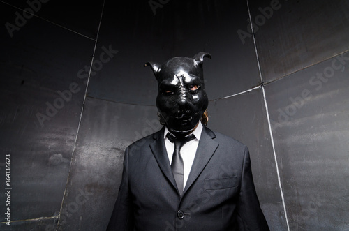Photos A corporate man in a dirty scruffy suit wearing a black pigs mask in a dark sinister background, photographed with moody cinematic lighting