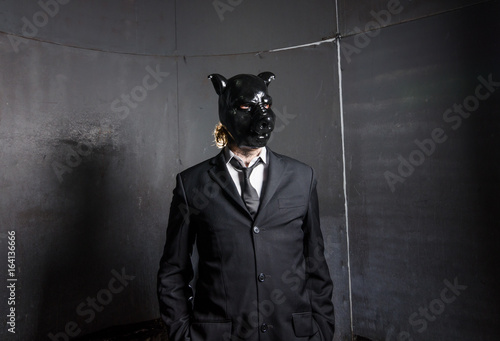 A corporate man in a dirty scruffy suit wearing a black pigs mask in a dark sinister background, photographed with moody cinematic lighting. evil dirty corporate pigs.