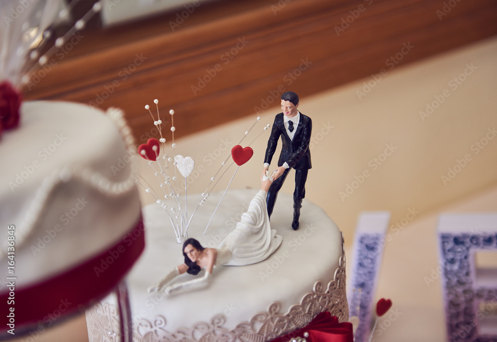 A sweet creamy Wedding cake with beautiful flowers and decorations, with 3d printed funny bride and with a shallow depth of field. Love words. Stock Photo | Adobe