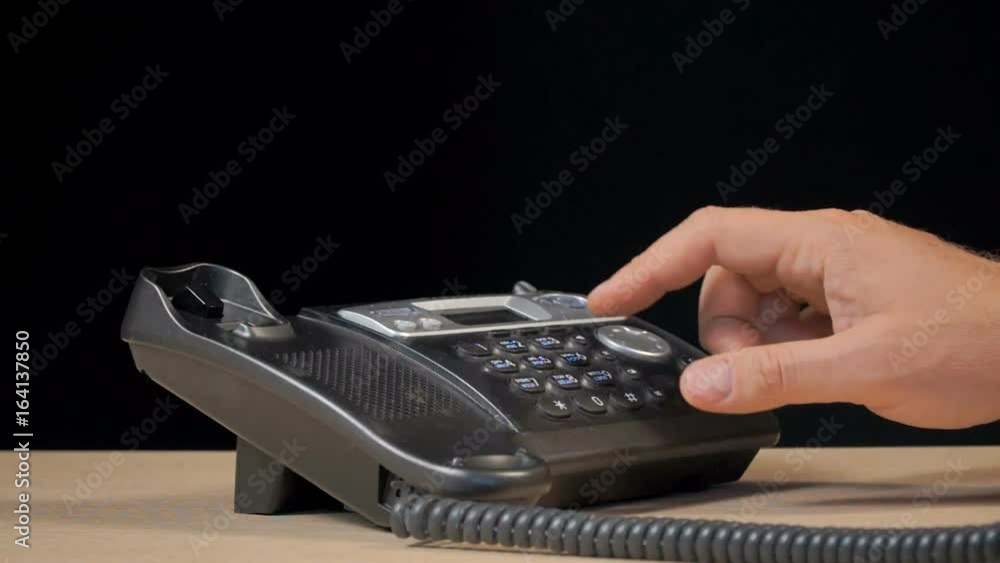 Shooting in the studio on a black background. The man's hand uses a wired phone. Shooting in the studio on a black background. The man's hand uses a wired phone.