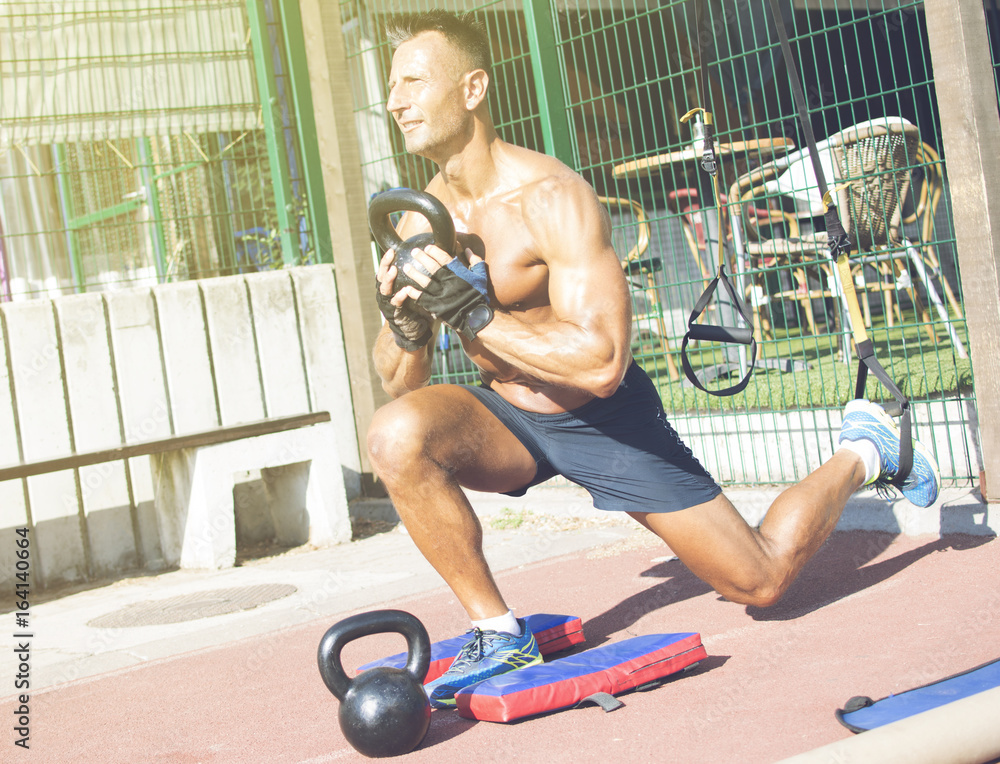 © Addoro - Handsome middle aged man working out on a running track. Healthy adult man doing step up using a kettlebell on the track. Tanned skin and shirtless middle-aged man. © Addoro - Handsome middle aged man working out on a running track. Healthy adult man doing step up using a kettlebell on the track. Tanned skin and shirtless middle-aged man.
