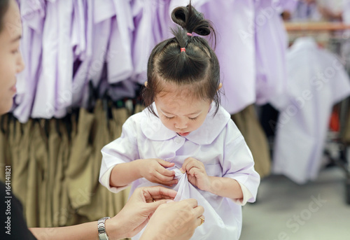 Mother try dressing school uniform for her daughter, Kindergarten children. photo