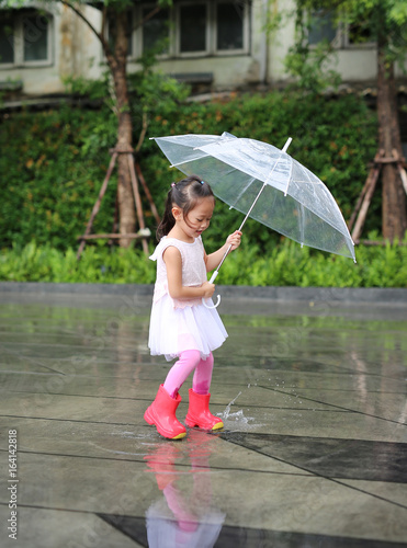 Cute little girl with umbrella in the rain.