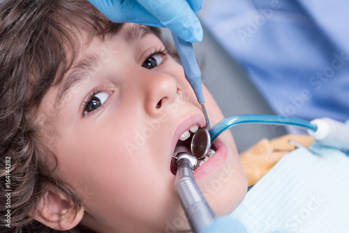 dentist examining teeth of little boy in dental hospital