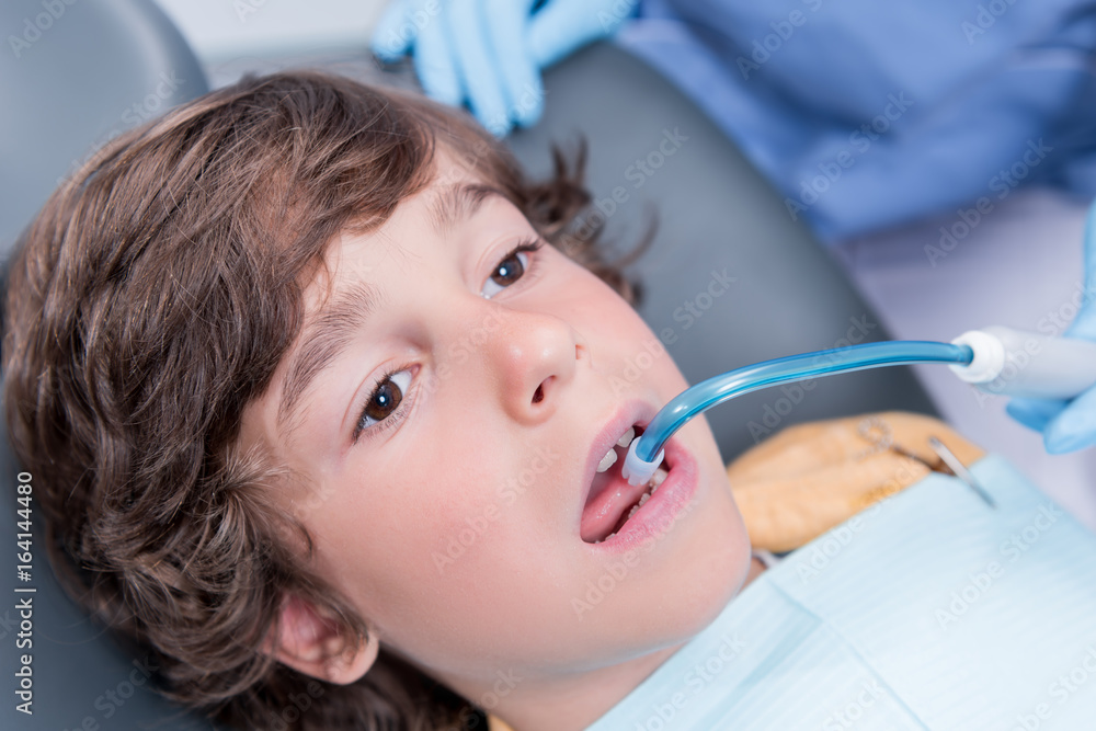 close up view of dentist treating teeth of little boy in dentist office