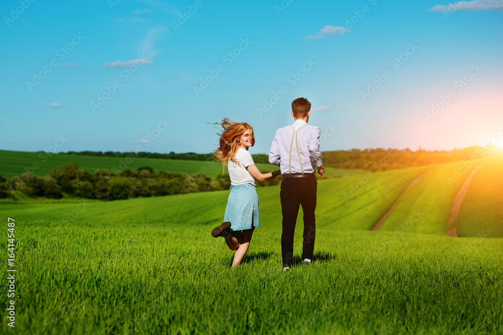 Young couple running along a green field on a lovely sunny day Young couple running along a green field on a lovely sunny day