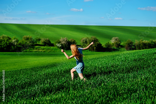 Young beautiful woman running on a green field © cezarksv
