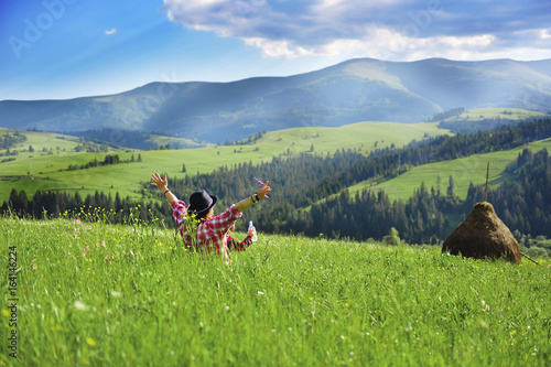 Young mother sitting with her young son in a meadow in the mountains in the summer.