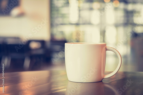 Coffee cup on the table in coffee shop - vintage tone with soft focus