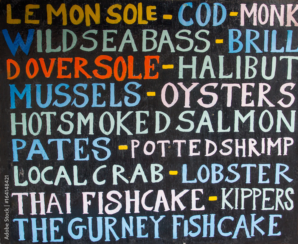 A fishmonger's sign listing the various different types of fresh fish and seafood available to buy. A fishmonger's sign listing the various different types of fresh fish and seafood available to buy.