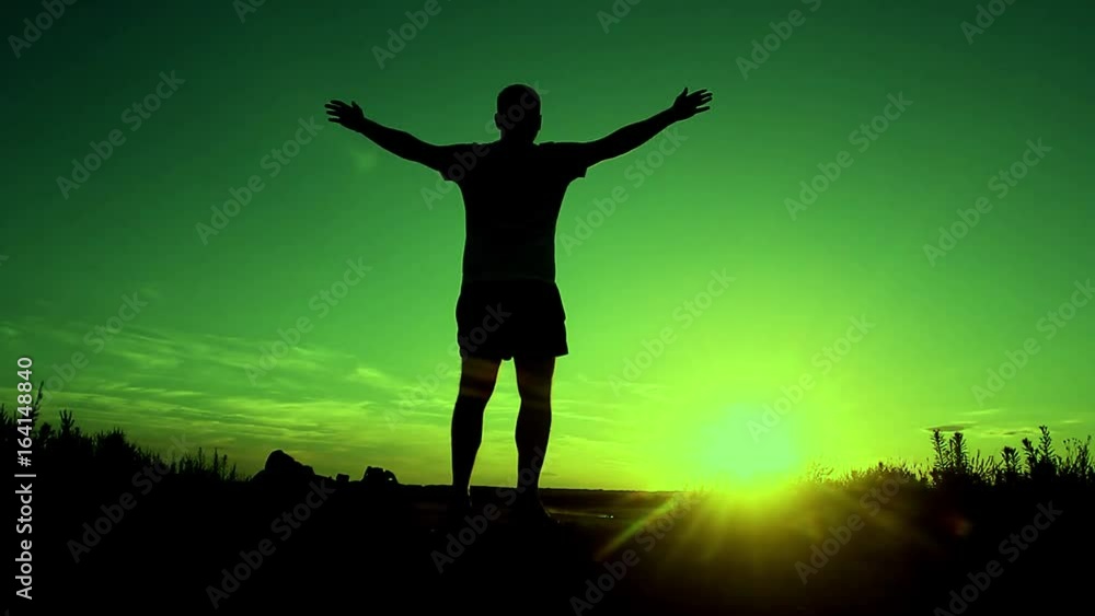 Silhouette of the people with a shoulder bag to see the sun Sky background. Man standing on the mountain with his arms wide open. Silhouette of the people with a shoulder bag to see the sun Sky background. Man standing on the mountain with his arms wide open.