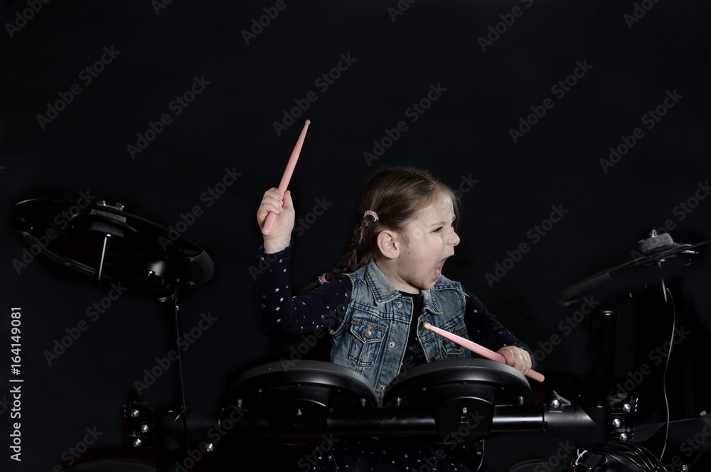 Fototapeta premium Little caucasian girl drummer play the elettronic drum kit