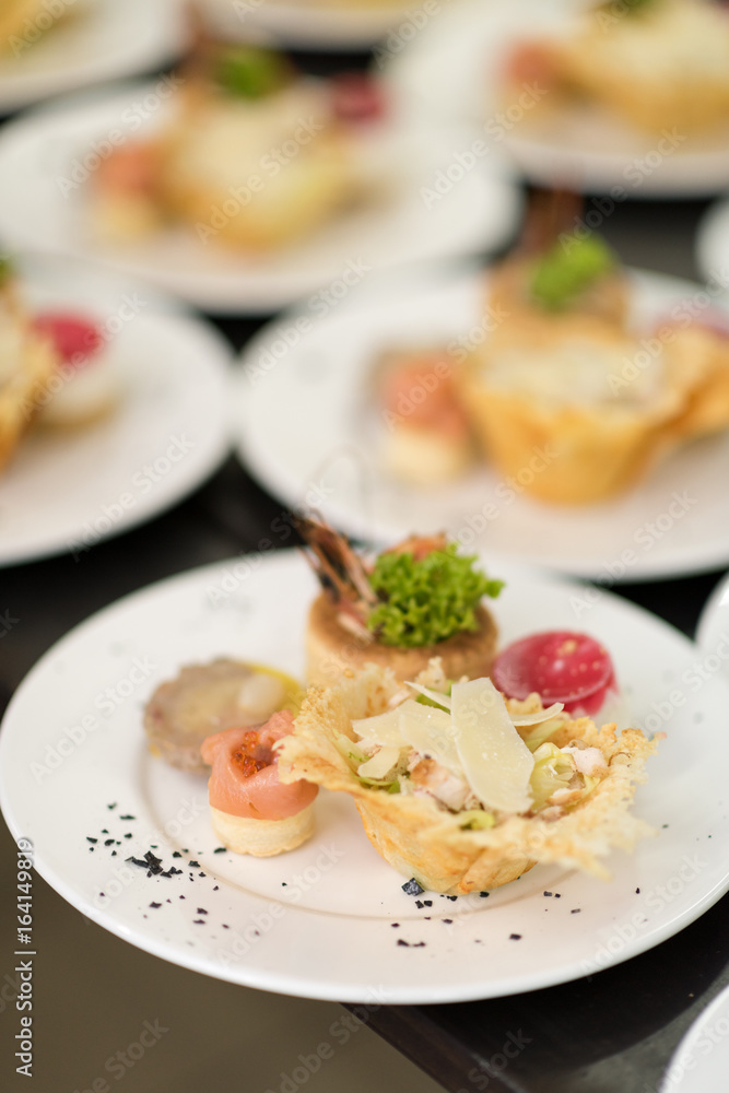 Many plates of appetizers being prepared in commercial kitchen, for an event