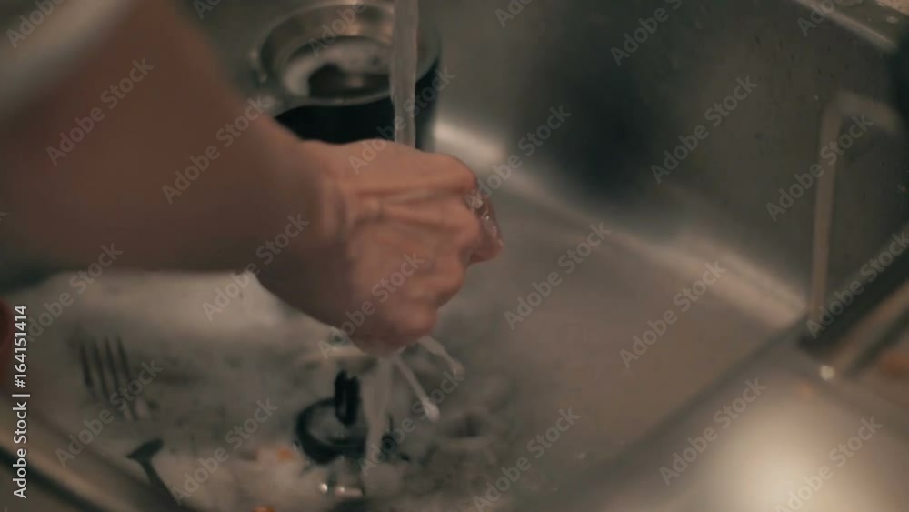 Closeup slow motion shot of a woman's hands washing the dishes. Closeup slow motion shot of a woman's hands washing the dishes.
