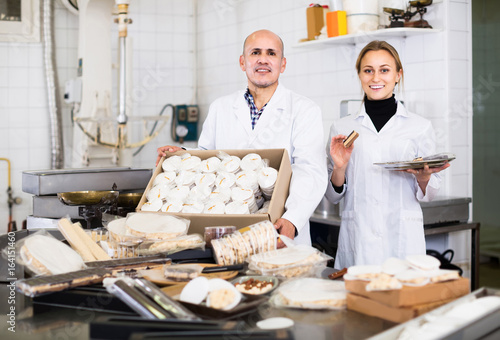 Different aged couple standing with box of turron in production workshop photo