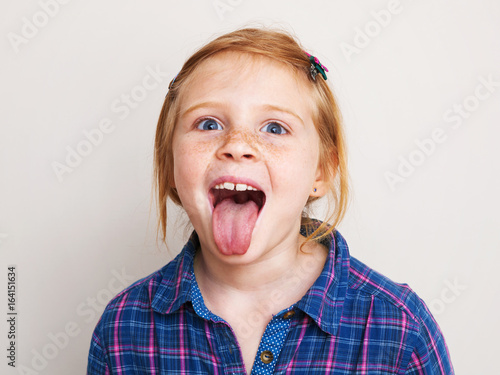 Принти на полотні Happy redhead little girl showing her tongue.