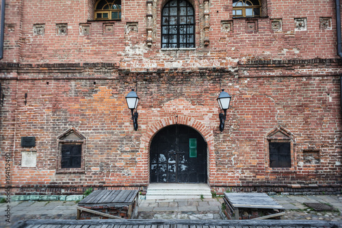 Forged lantern on a brick wall. Old red brick building with black metal door and windows