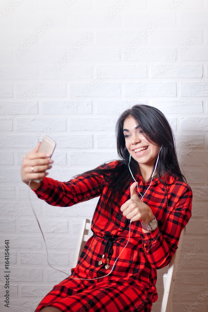 Brunette Woman taking selfie with her phone, white bricks background wall Brunette Woman taking selfie with her phone, white bricks background wall
