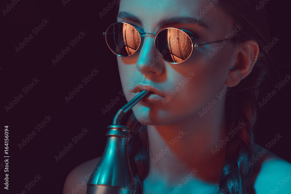 woman in round sunglasses drinking soda from water bottle with straw - obrazy, fototapety, plakaty 