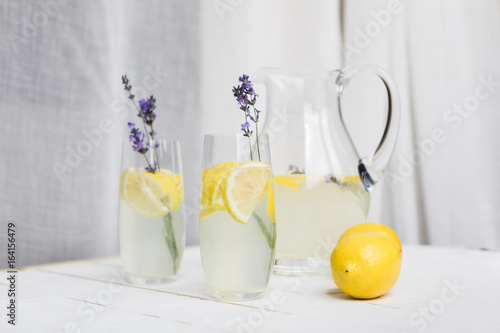close up view of citrus beverages with lavender in glasses and glass jar on wooden table