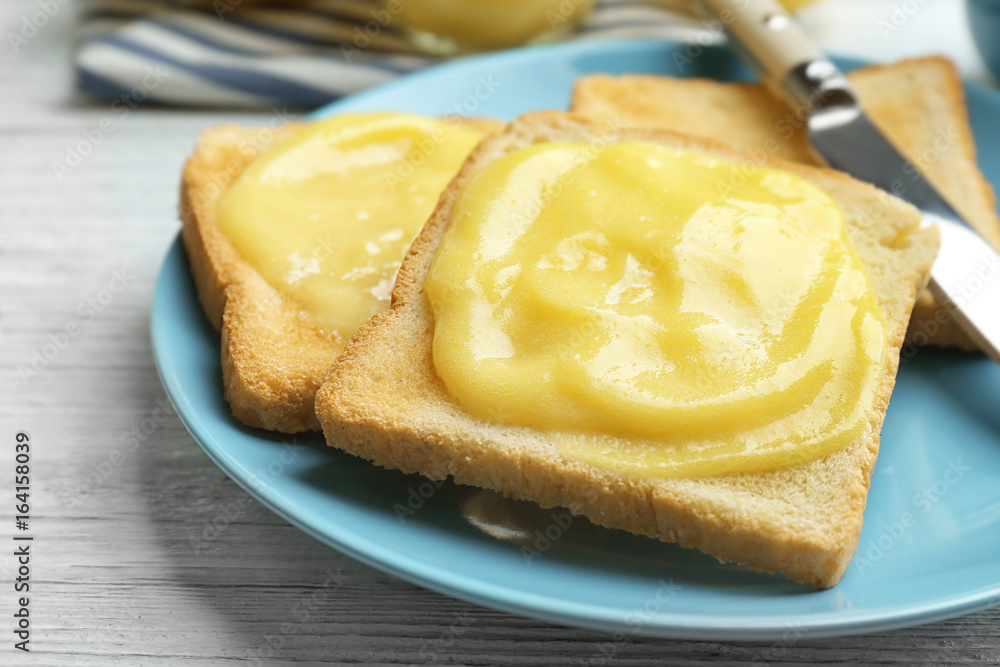 Plate with fresh toasts and delicious lemon curd on wooden table, closeup Plate with fresh toasts and delicious lemon curd on wooden table, closeup