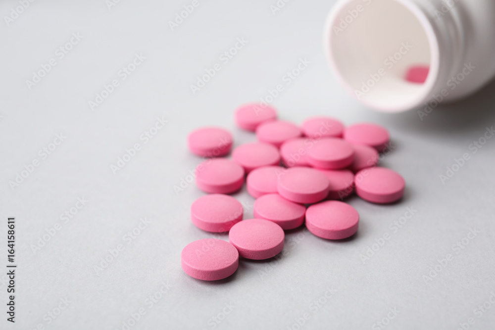 Plastic container and pills on light background Plastic container and pills on light background