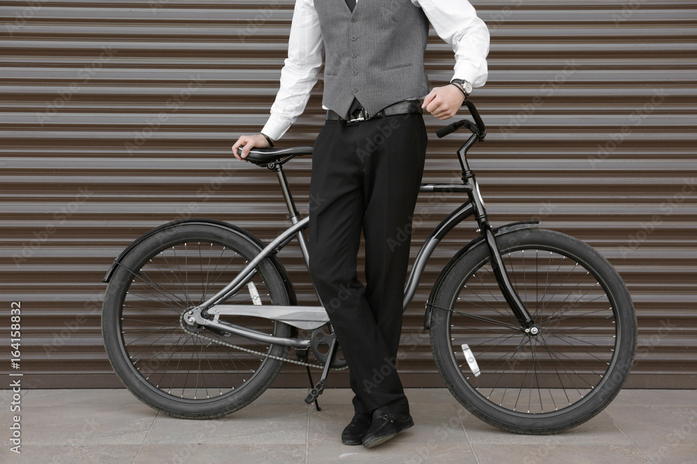 Fototapeta premium Young man with bicycle on color wall background
