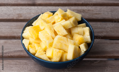 Pineapple slices in a blue ball on a wooden background © Anastasiia
