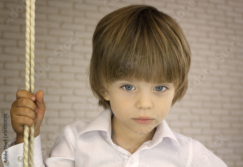 Blue-eyed boy in a white shirt with rope photo