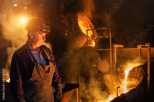 Φωτογραφία Foundry worker looking at falling in molten steel.