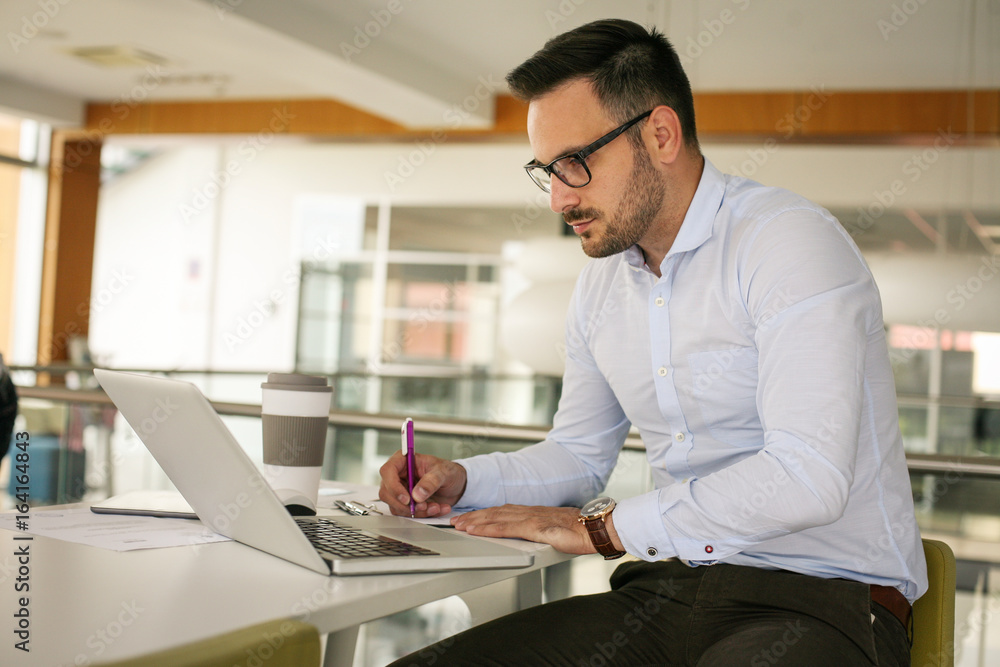Business man working in office on laptop and writing document. Business man working in office on laptop and writing document.