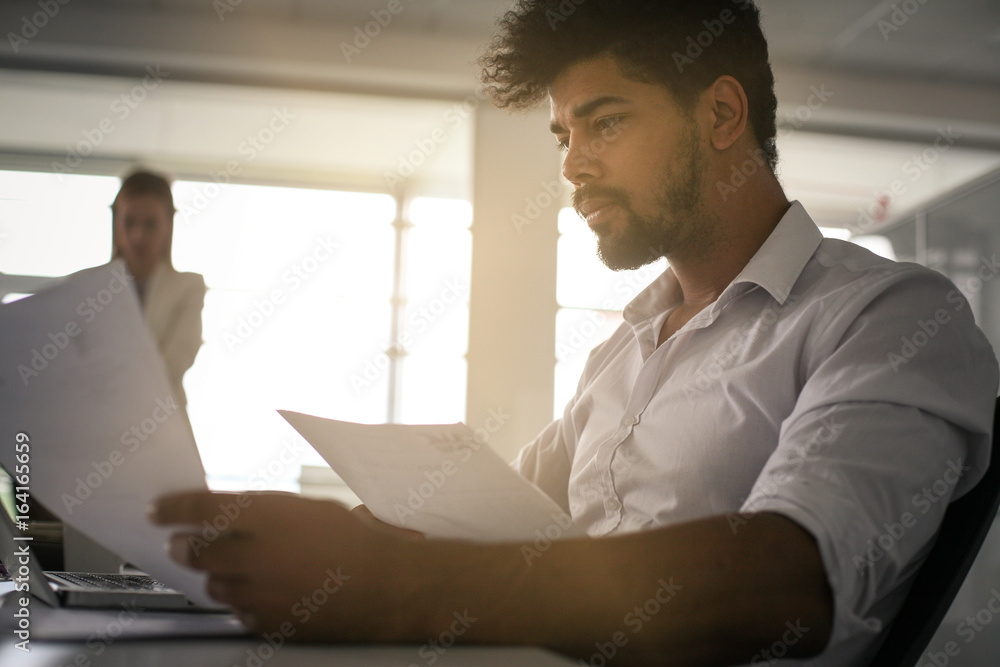 Business people in office. African business man reading document. Business people in office. African business man reading document.