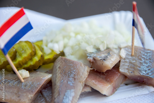 Broodje haring a traditional dutch snack, seafood sandwich with herring, onions and pickled cucumber. photo