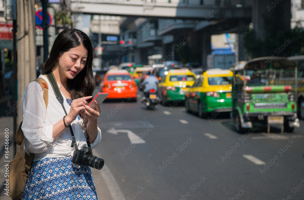 Obraz premium Asian backpacker woman using mobile phone app