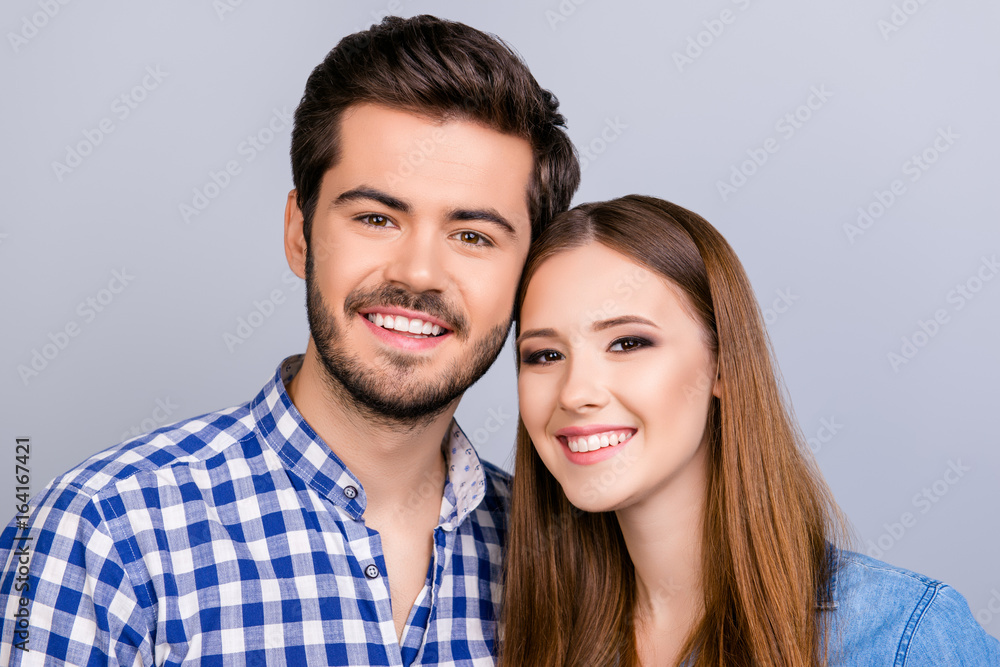 Family portrait. Two young cute lovers are looking at the camera and smile, wearing casual outfits, bonding on the pure background Family portrait. Two young cute lovers are looking at the camera and smile, wearing casual outfits, bonding on the pure background