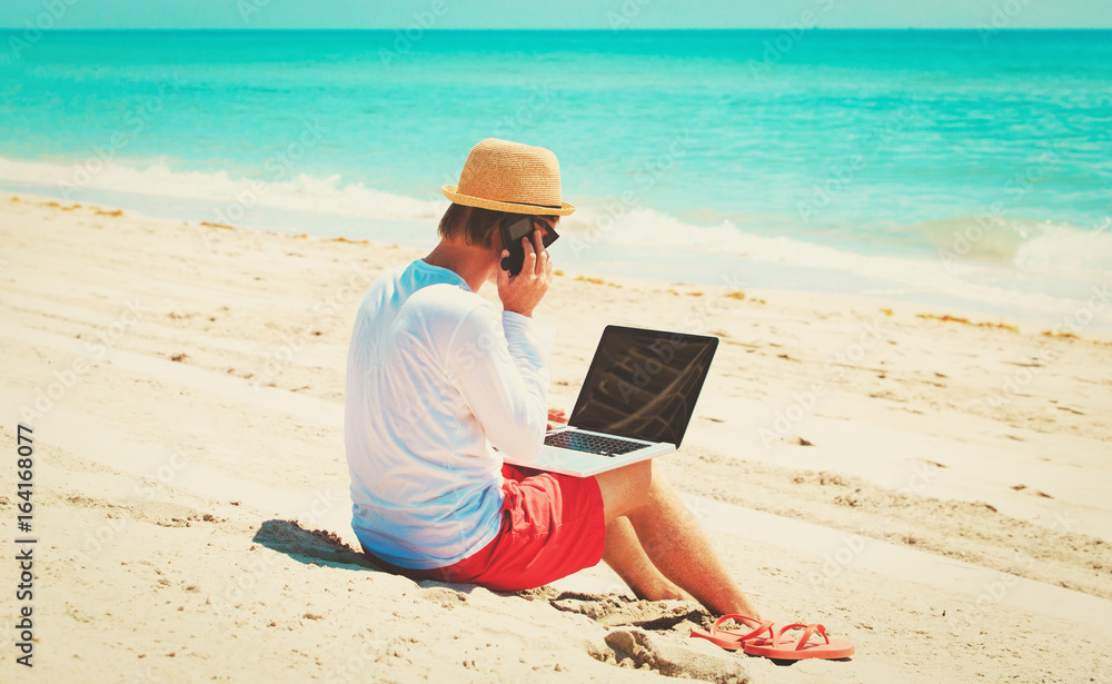 man with laptop and mobile phone on beach