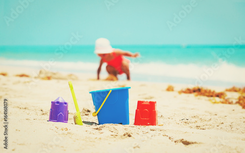 kids toys and little girl playing on beach