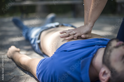 ragazza esegue rianimazione cpr con massaggio cardiaco a giovane svenuto dopo arresto cardiaco © pixelaway