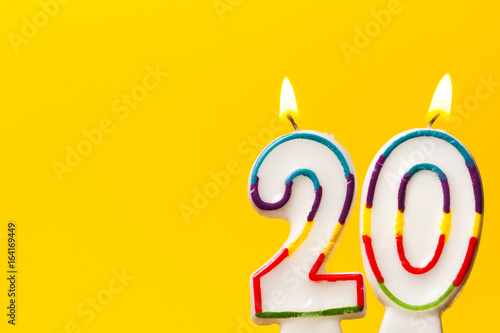 Number 20 birthday celebration candle against a bright yellow background photo