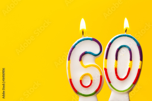 Number 60 birthday celebration candle against a bright yellow background