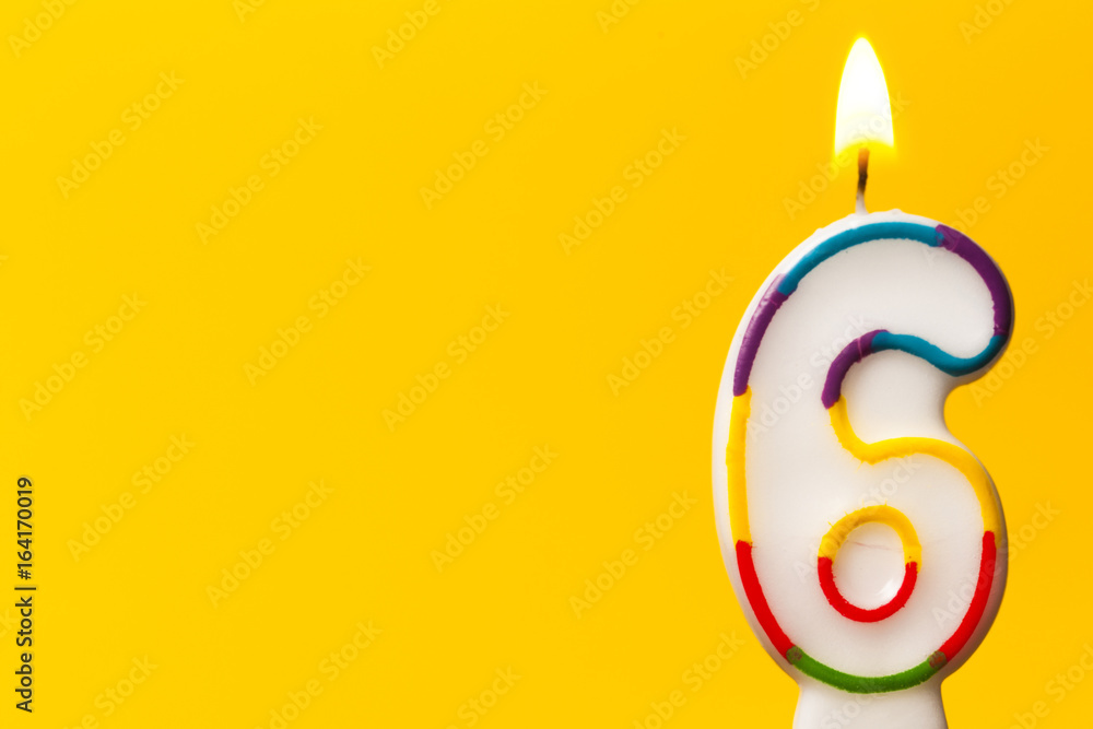 Number 6 birthday celebration candle against a bright yellow background Number 6 birthday celebration candle against a bright yellow background