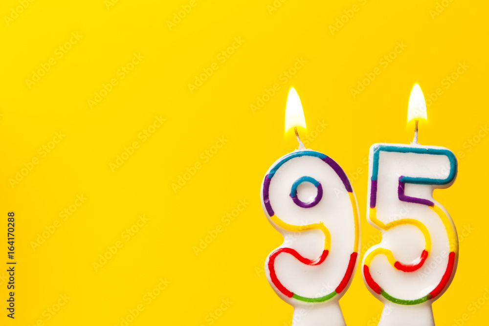 Number 95 birthday celebration candle against a bright yellow background Number 95 birthday celebration candle against a bright yellow background