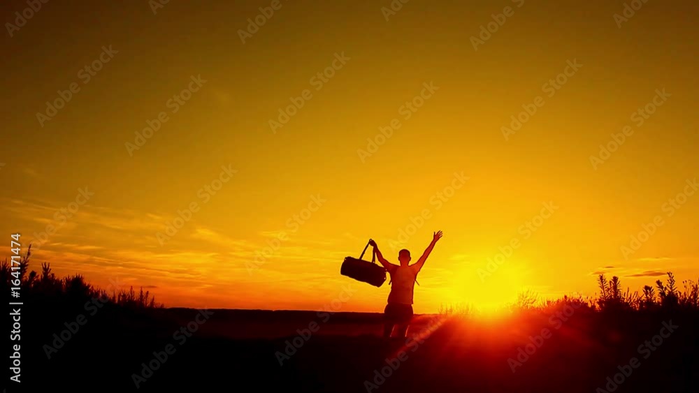 Silhouette of the people with a shoulder bag to see the sun Sky background. Man standing on the mountain with his arms wide open. Silhouette of the people with a shoulder bag to see the sun Sky background. Man standing on the mountain with his arms wide open.